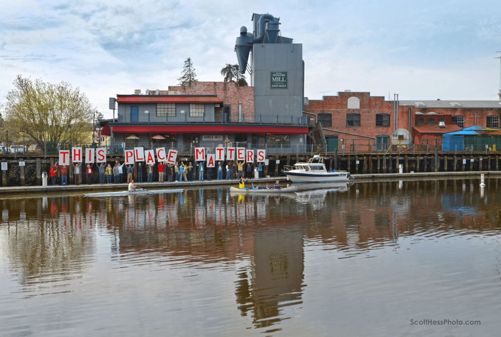 The Trestle on the Petaluma riverfront, with community members on the boat docks holding up letters spelling "This Place Matters."