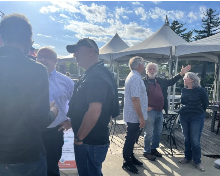 Screen shot of Petaluma Patch article's lead picture. It shows Petaluma Trestle Promenade Now members talking the the public on the wharf between Riverfront cafe and the Trestle. Our chair - Mayor McDonnell is facing the camera talking to two people on the left of the picture.