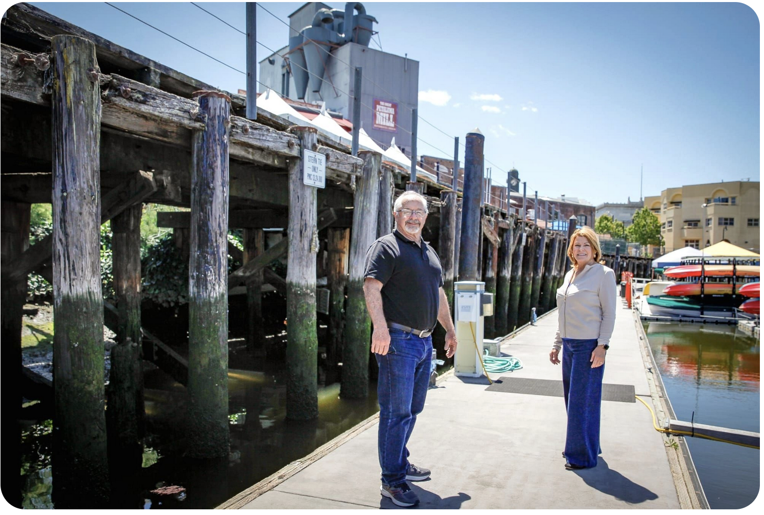 Screen shot from headline image in Petaluma Voice article. Mayor Kevin McDonnell and member Rosemary Hart are standing on the docks in front of the trestle. The Great Petaluma Mill is in the background.